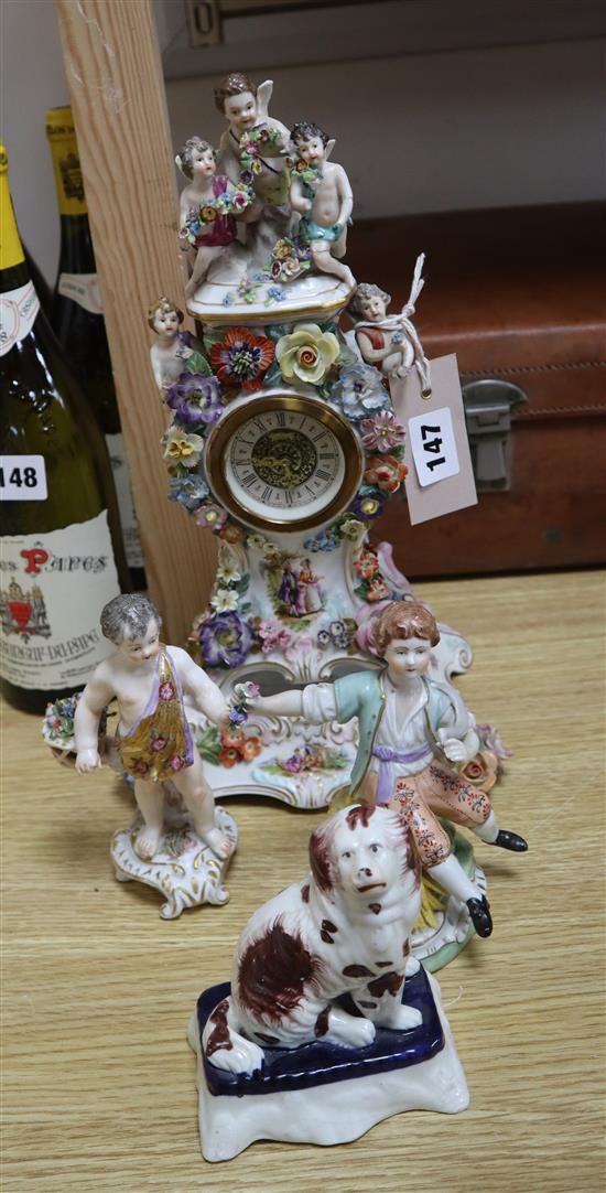 A Dresden porcelain mantel clock, two similar figures and a Staffordshire dog clock 30cm